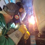 QMS tech torch-cutting galled bolts to remove a seized flange.