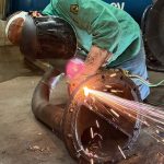 QMS technician welding a pipe flange to restore a process line.