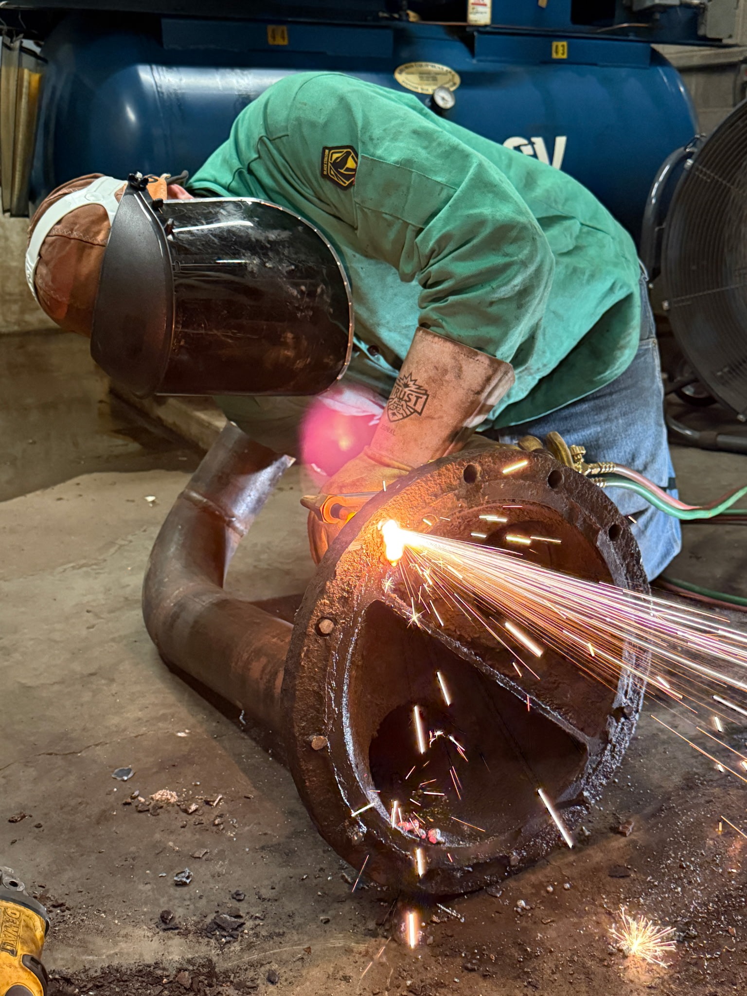 QMS technician welding a pipe flange to restore a process line.
