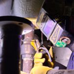 QMS welder tacking a spacer plate into position to correct alignment.